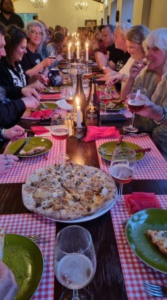 Gedeelde tafel met mensen die genieten van een diner met kaarslicht, pizza en bier.