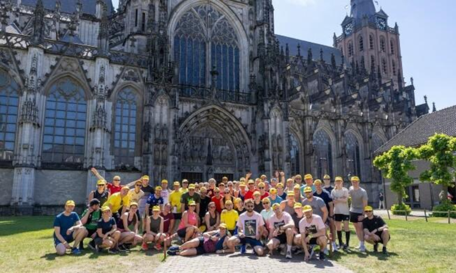 Groep mensen met gele petten voor kathedraal tijdens Bierrun en -walk Den Bosch.