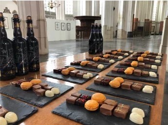 Bierflessen en chocoladerepen op leisteen in kerk voor proeverij.