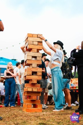Mensen spelen een groot Jenga-spel op een buitenfestival.