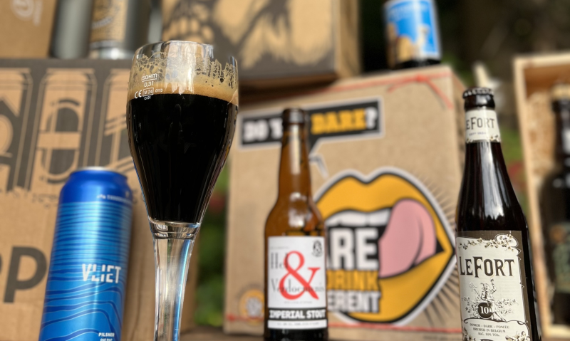 Donker bier in een glas met andere bieren en bierpakketten