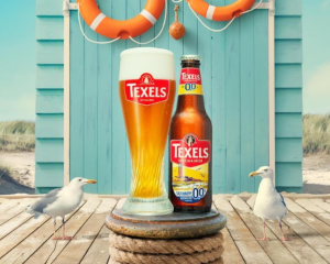 Skuumkoppe 0.0 flesje en glas op het strand met twee meeuwen ernaast