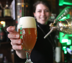 barvrouw geeft getapt Heineken Mokum 750 bier aan
