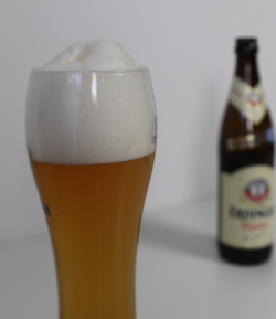 Duits Weizen bier schuimkraag met een flesje Erdinger Hefe Weisse op de achtergrond