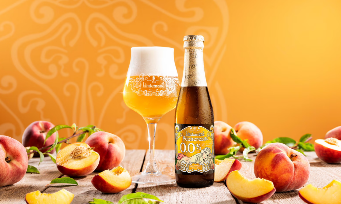 Lindemans Pecheresse 0,0% bier flesje en glas tussen perzikken in
