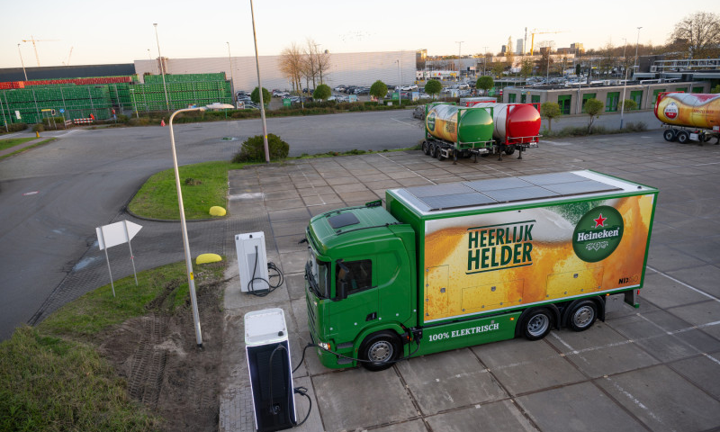 Elektrische Heineken truck bij laadstation op parkeerplaats.