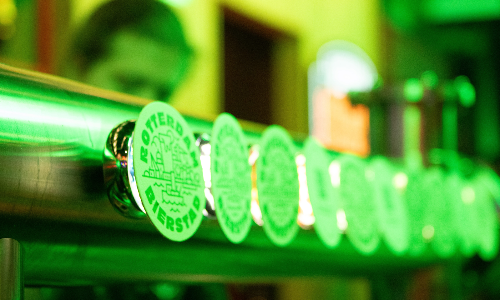 Groene bierzuil met Rotterdam bierlogo's in een baromgeving.