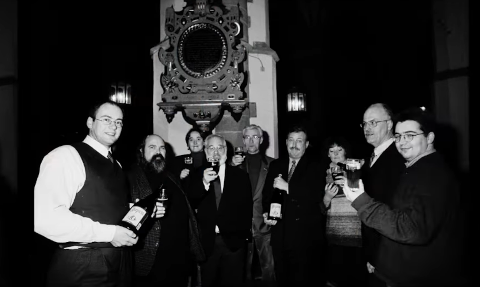 Groep mensen houdt Jopen bier omhoog in een historische setting.