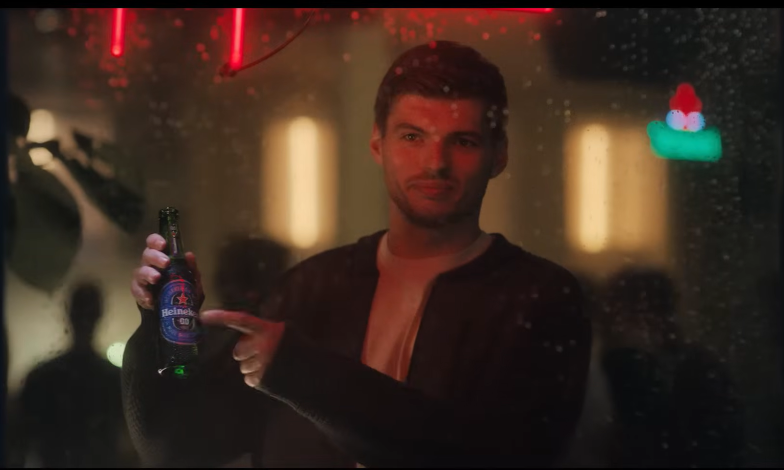 Man wijst naar fles alcoholvrij bier door nat raam.