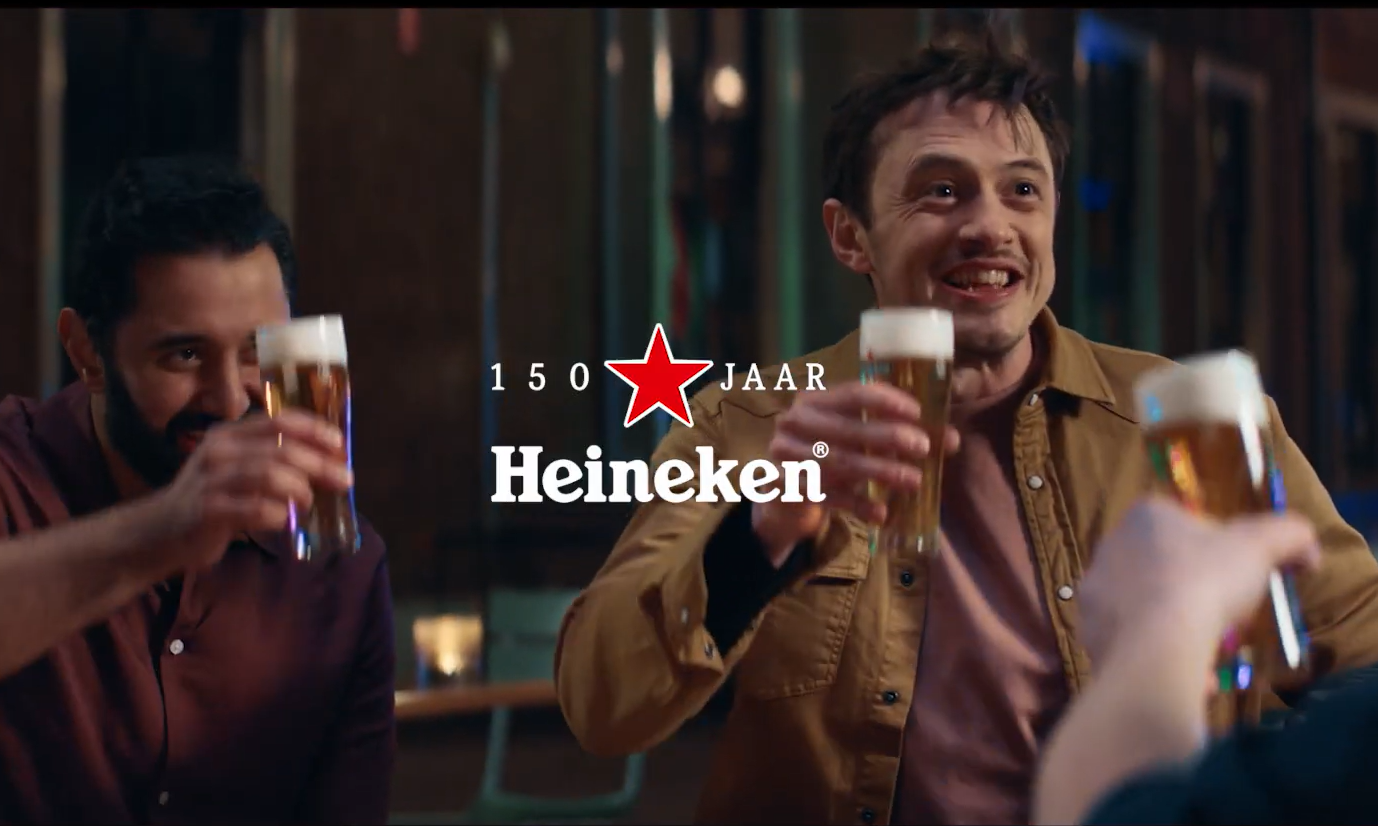 Twee mannen proosten met Heineken bier in een bar, met het logo van Heineken en 150 jaar.