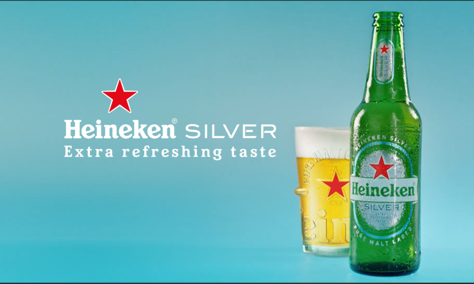 Een fles Heineken Silver bier naast een glas bier met schuim op een blauwe achtergrond.
