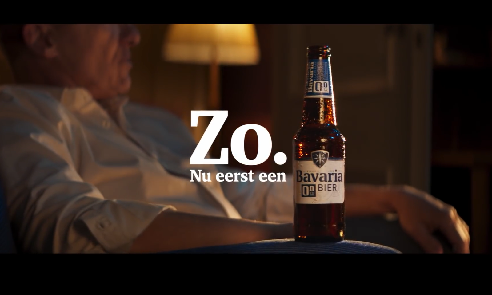 Man in stoel met een fles Bavaria 0.0% bier en tekst 