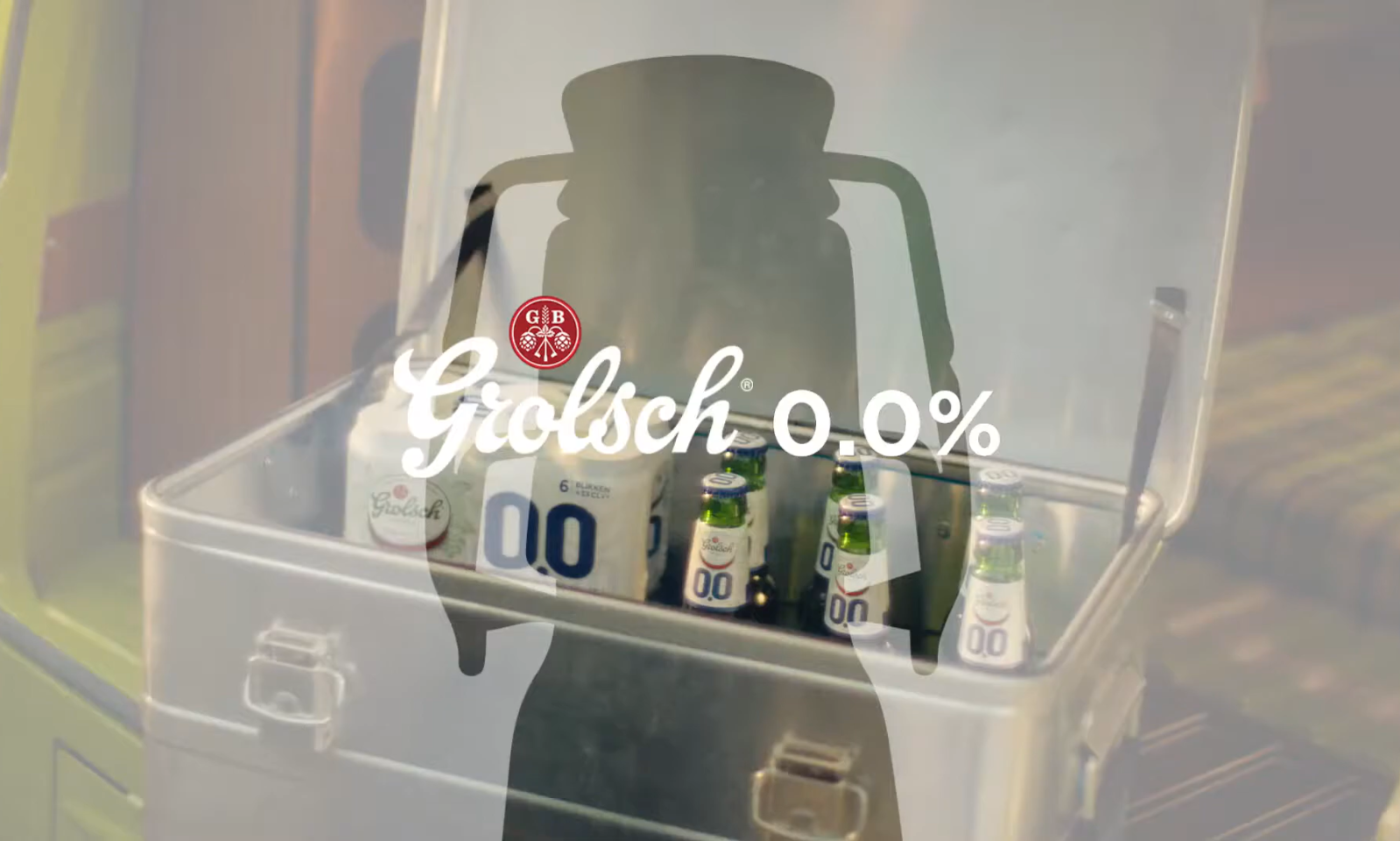 Grolsch 0.0% flesjes in een open metalen koelbox, met een schaduw van een persoon.