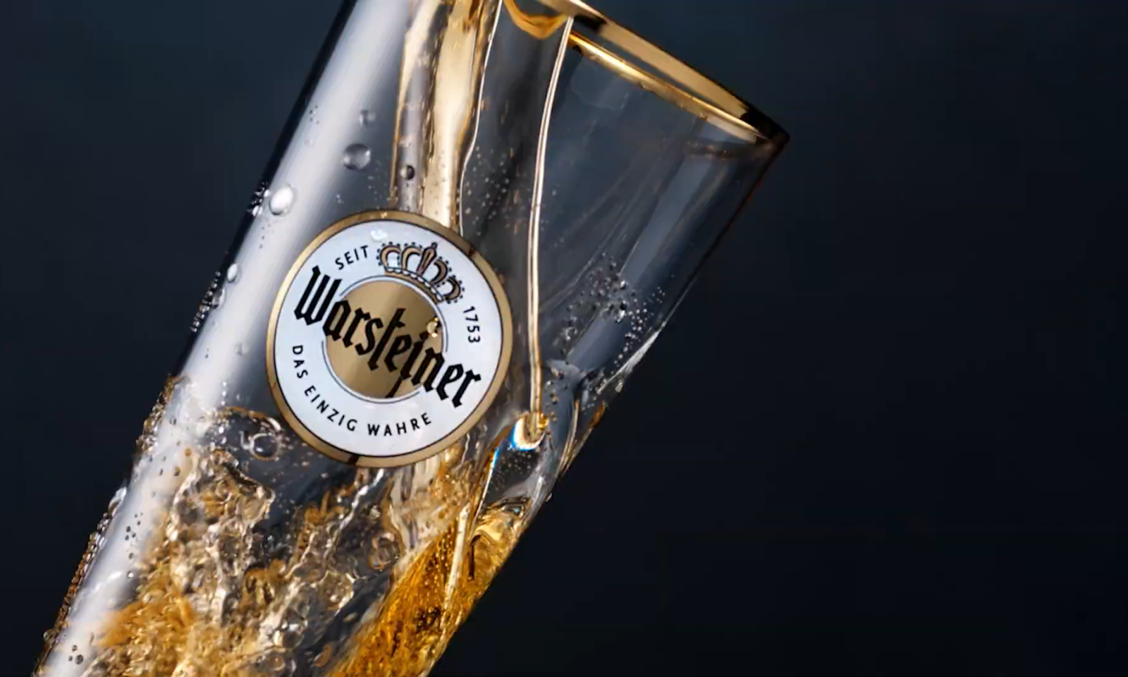 Glas Warsteiner bier met schuimende gouden vloeistof tegen donkere achtergrond.
