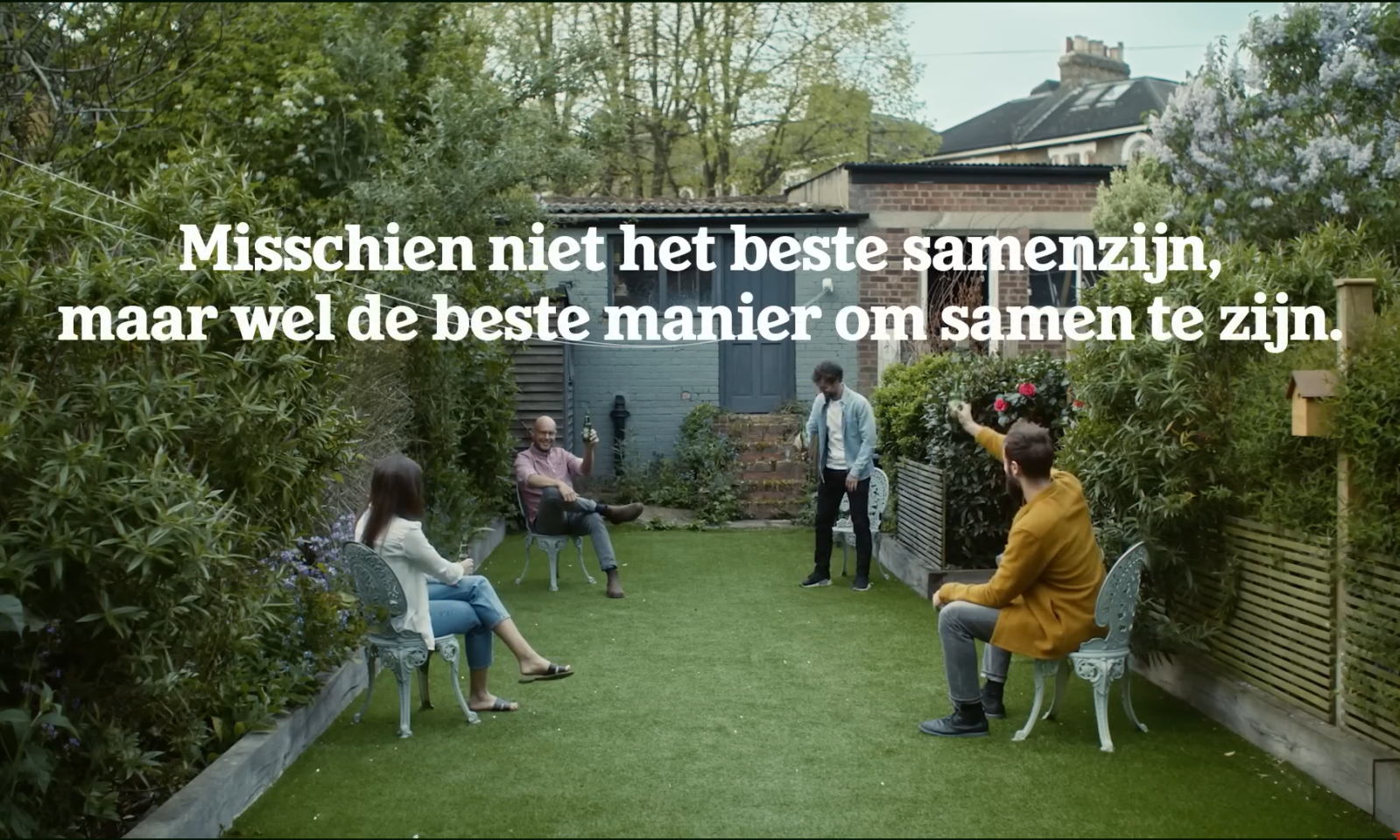 Vier mensen in een tuin op afstand zittend, met tekst over socializen.