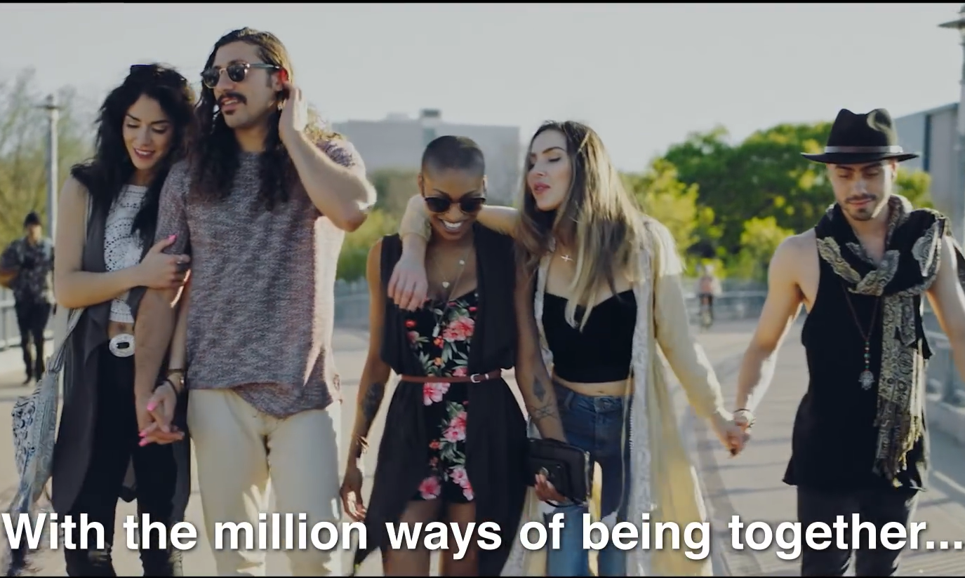 Vijf mensen lopen samen op een zonnige dag over een brug.