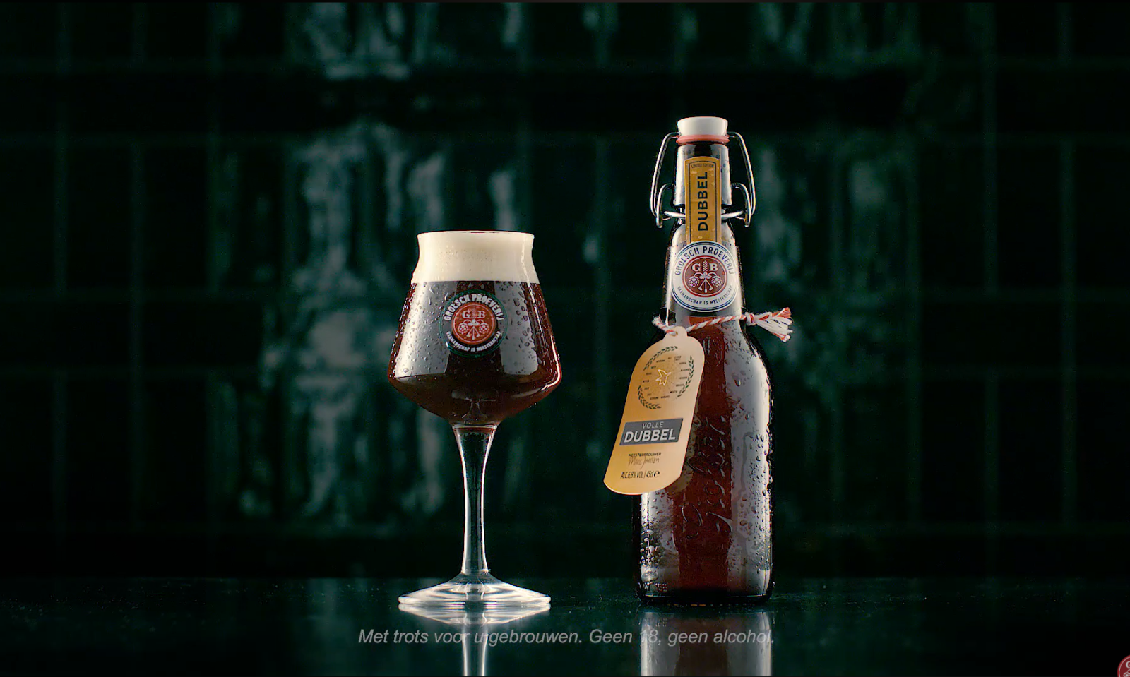 Een glas en een fles Grolsch Dubbel bier op een donkere achtergrond.