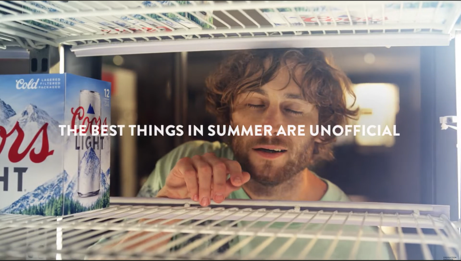 Man voor open koelkast, doos Coors Light bier zichtbaar.