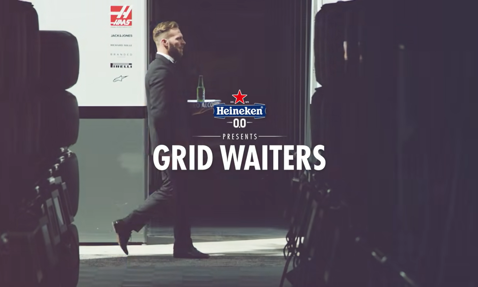 Man in pak met dienblad en Heineken 0.0 fles tussen bandenstapels.