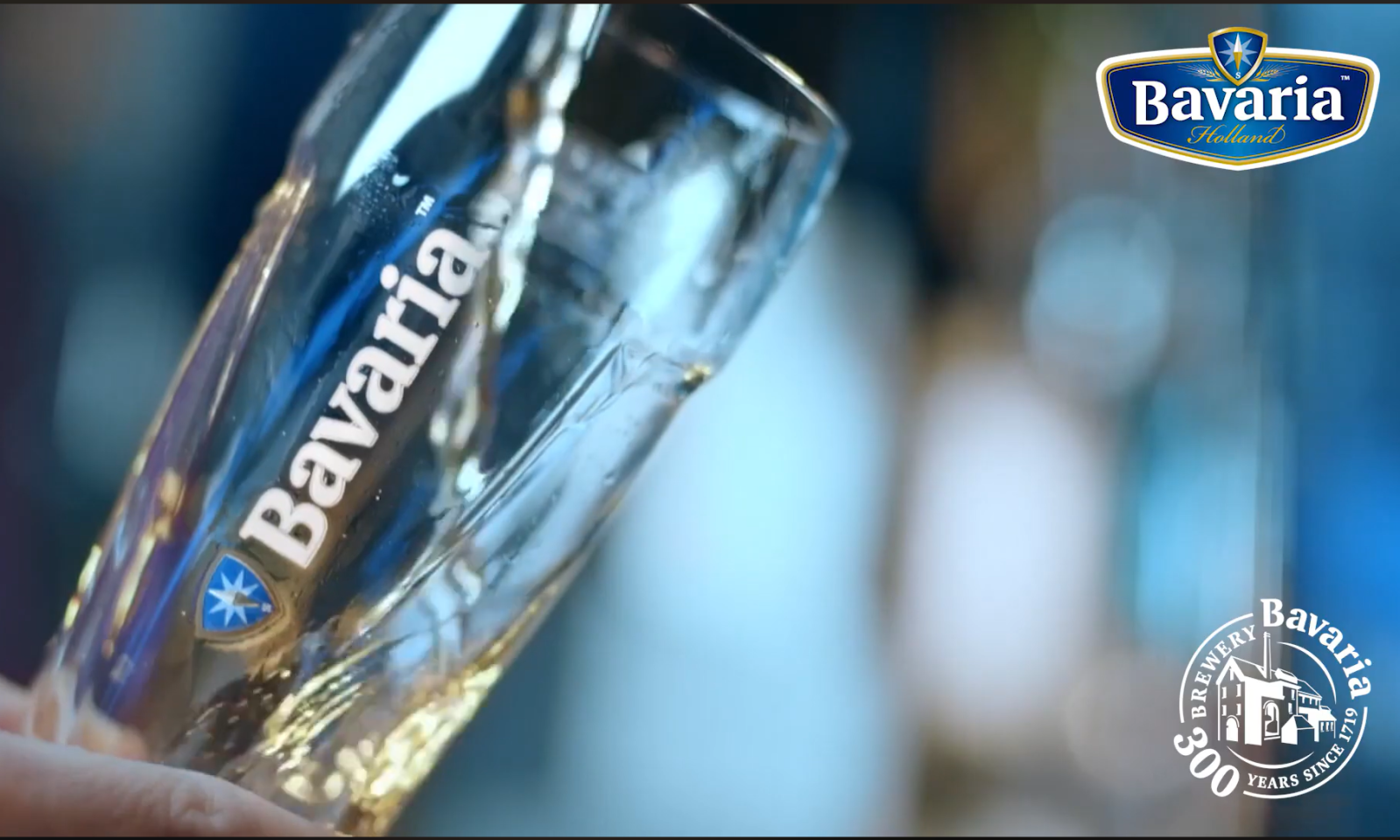 Close-up van een glas met Bavaria-logo en inschenken van bier.