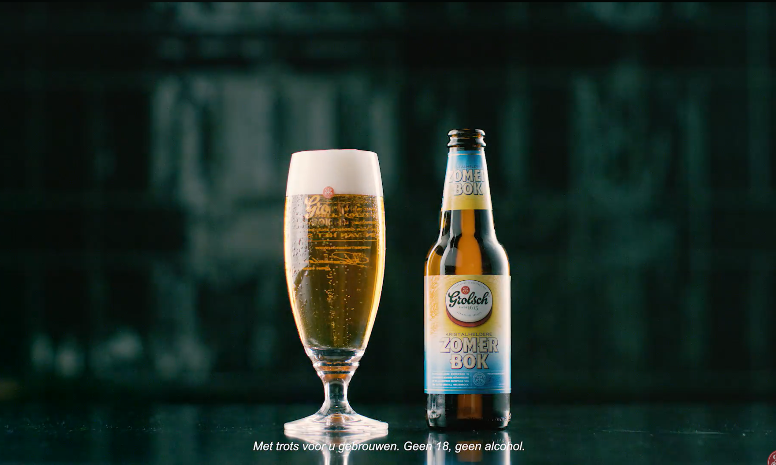 Grolsch bierglas en flesje Zomerbok op donkere achtergrond.