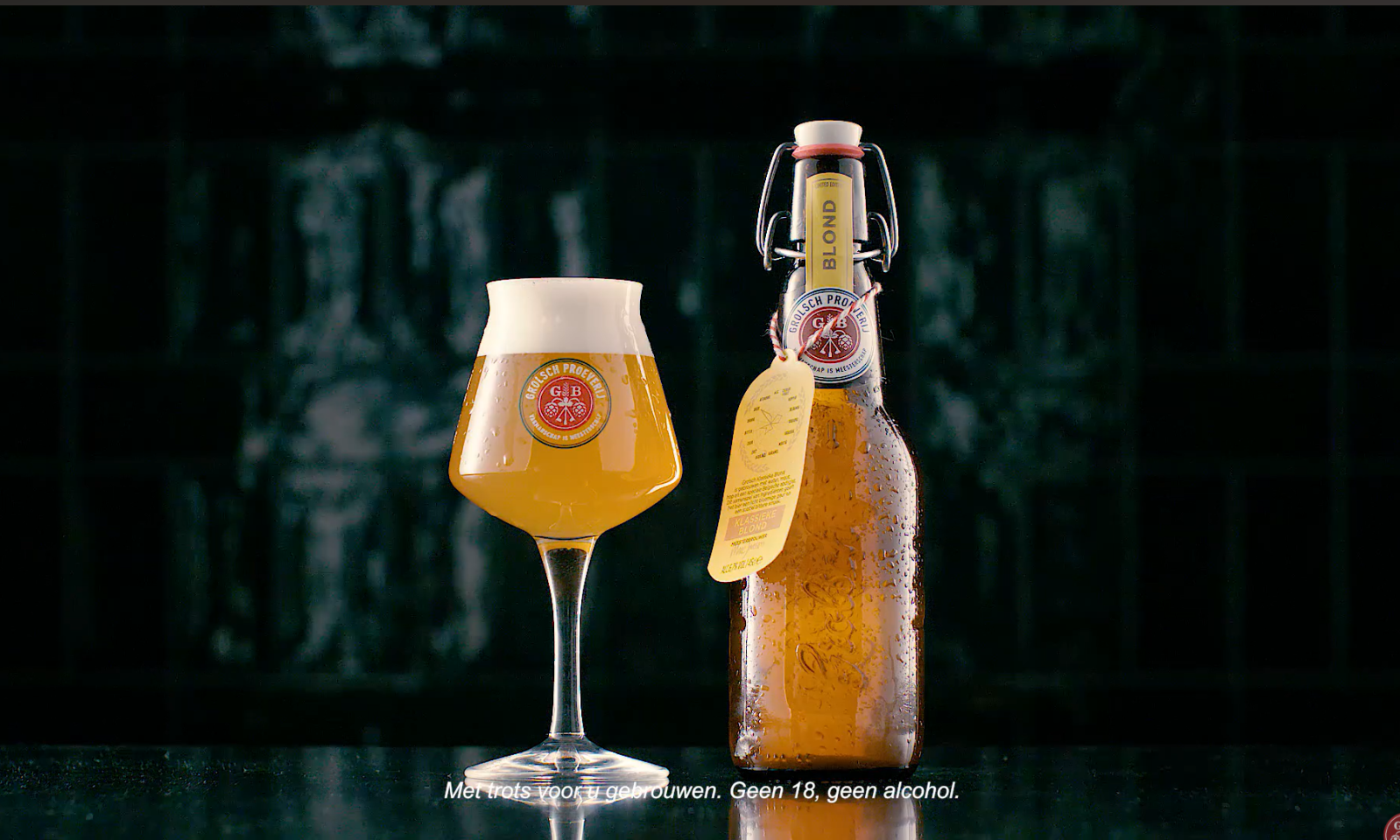Glas Grolsch Klassieke Blond naast een Grolsch fles met druppels op een donkere achtergrond.