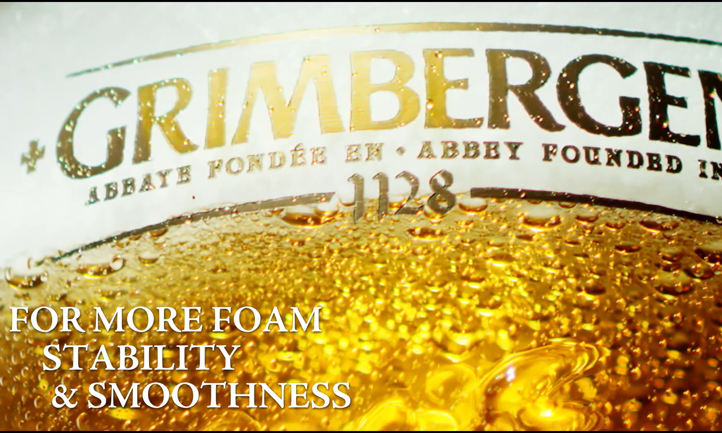 Close-up van een Grimbergen bierglas gevuld met goudkleurig bier en tekst over schuimstabiliteit.