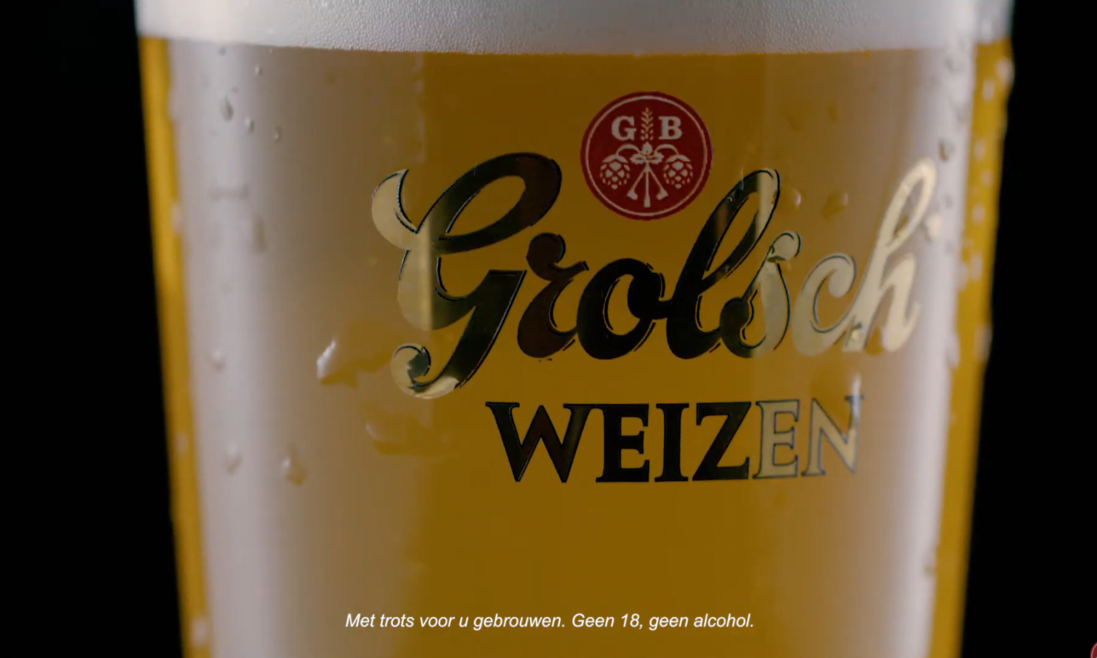 Glas gevuld met helder Grolsch Weizen bier met schuimkraag en logo zichtbaar.