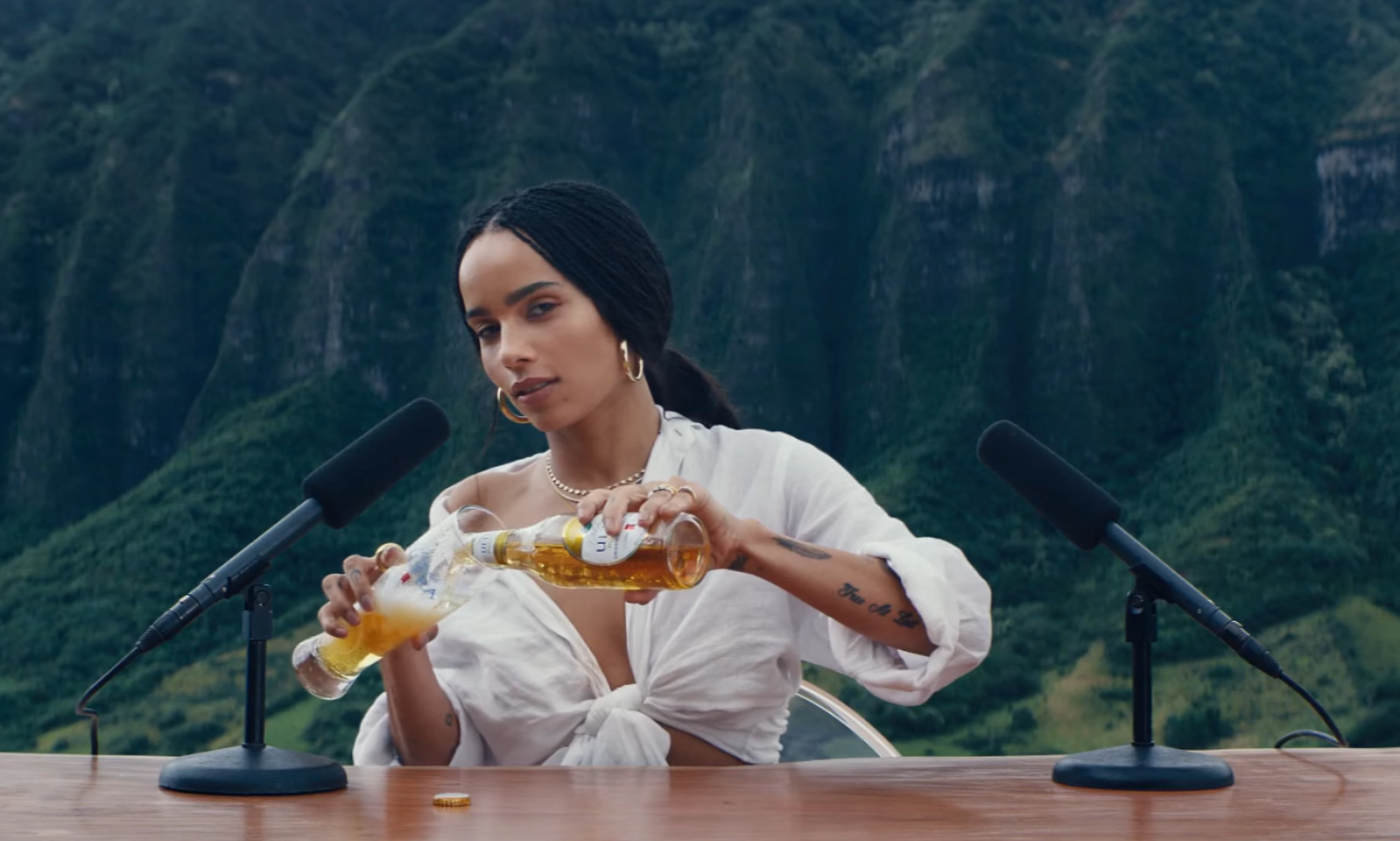 Vrouw schenkt bier in een glas met bergen op de achtergrond.