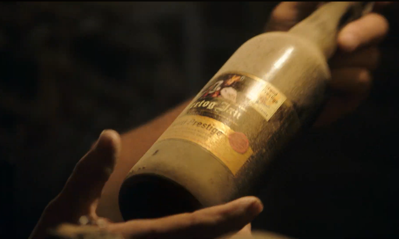 Close-up van een stoffige bierfles die wordt vastgehouden in een hand.