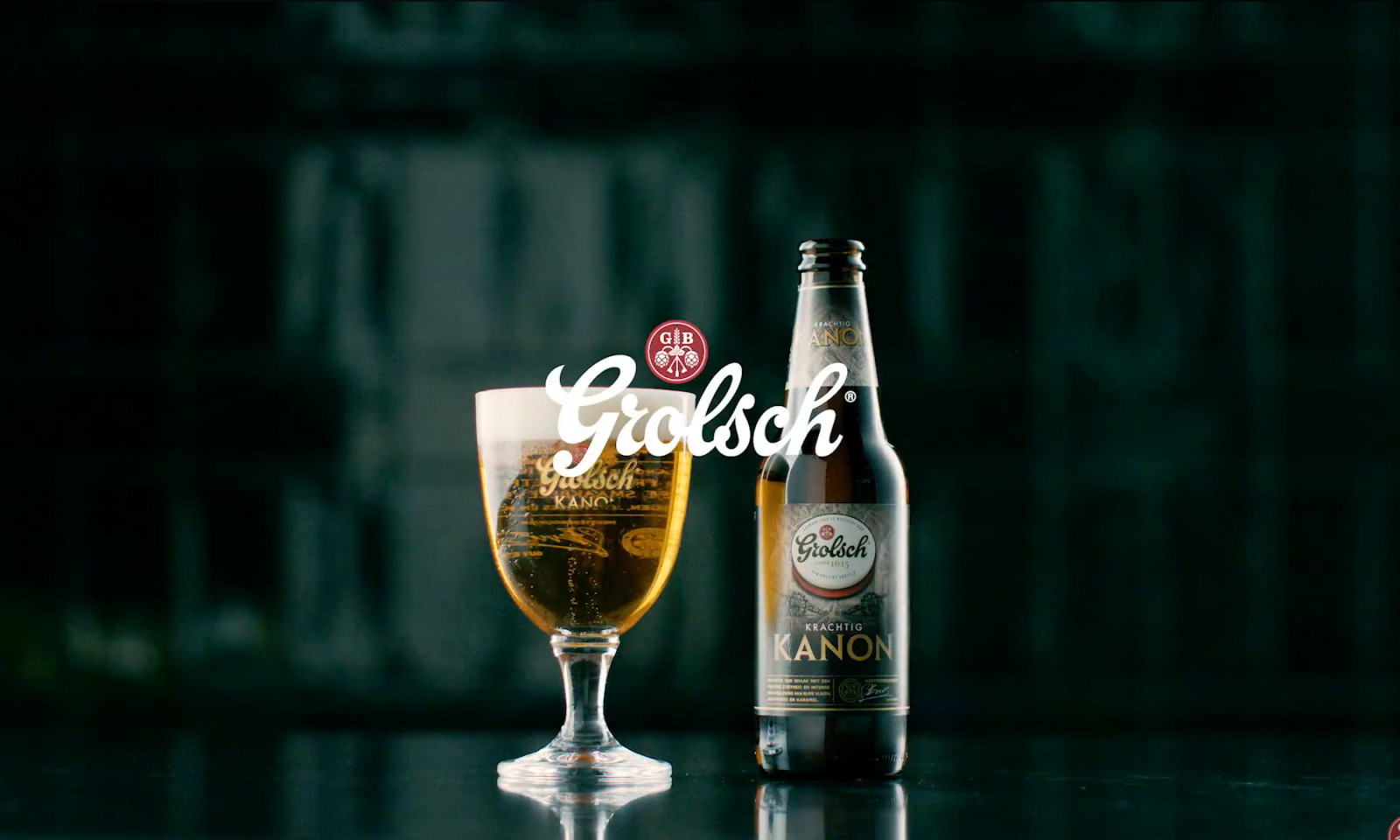 Glas en fles Grolsch Krachtig Kanon bier op een donkere achtergrond.