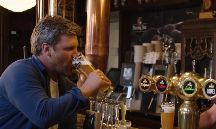 Twee mannen proosten met glazen bier aan de waterkant.