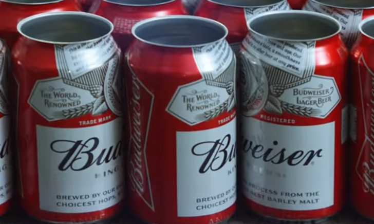 Productielijn met duizenden Budweiser blikken in een fabriek, met werknemer in rood uniform.