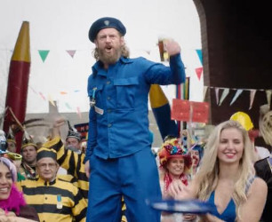 Drie mensen met een houten lijst, man in blauw uniform houdt bierglas vast.