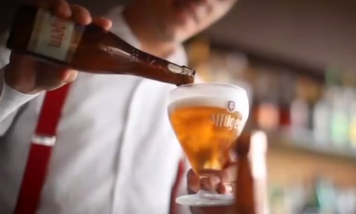 Twee glazen met Affligem bier op een houten tafel tijdens het schenkritueel.