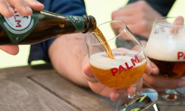 Groep mannen die proosten met glazen bier in een café, lachend en vrolijk.