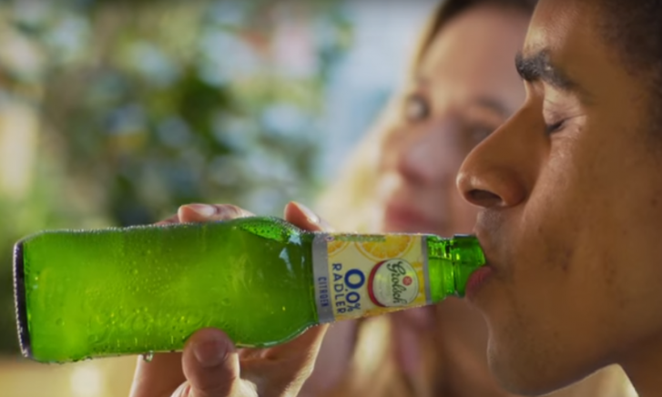 Groene fles Grolsch 0,0% Radler Citroen op tafel met wazige achtergrond.