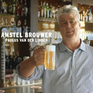 Amstel Pilsener Ongefilterd verpakking en flesje op een rots met blauwe lucht.