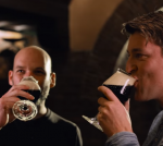 Mensen proosten met donker bier in een sfeervolle ruimte.