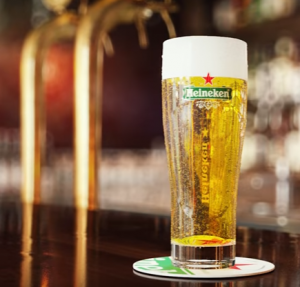 Glas Heineken bier op een bierviltje met tekst in een baromgeving.