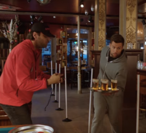 Drie mannen verplaatsen bierkratten en vaten in een opslagruimte.