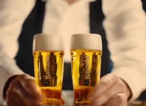 Groep vrienden die proostend bierglazen vasthouden in een drukke bar.