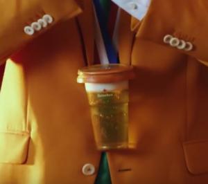 Man in oranje pak klapt met een biertje in zijn hand te midden van een juichende menigte.