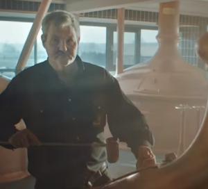 Man drinkt een glas Hertog Jan pilsener met schuimkraag.