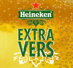 Een fles Heineken bier verpakt in wit papier met het label Extra Vers zichtbaar.