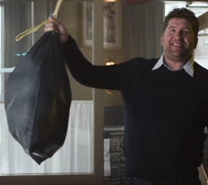 Hand plaatst een glas bier op een bierviltje op een houten tafel.
