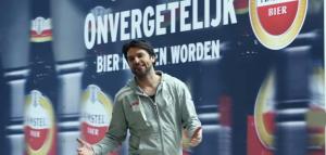 Man in een fabriek met rode Amstel bierkratten om zich heen, dragend een veiligheidsbril en fluorescerend jack.