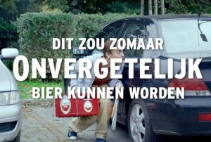 Vijf mannen drinken bier onder een rood parasol op een stadsplein.