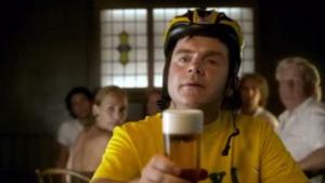 Grote groep mensen in een brouwerij met een fietser die een glas bier vasthoudt.