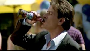 Drie mannen staan buiten bij een feestje met ballonnen en drinken flesjes bier.